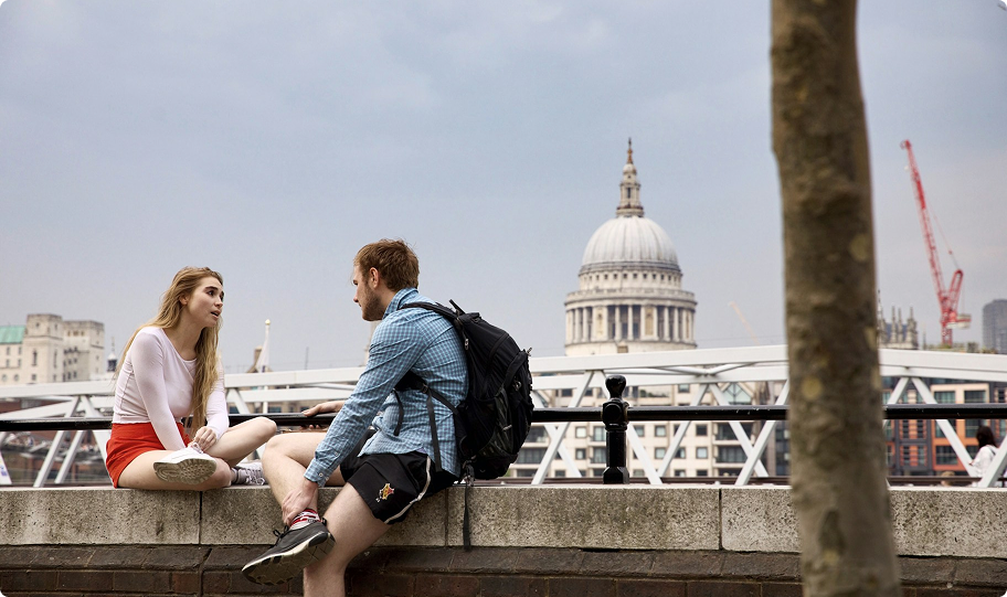 Two people sitting in front of St Paul's cathedral chatting.